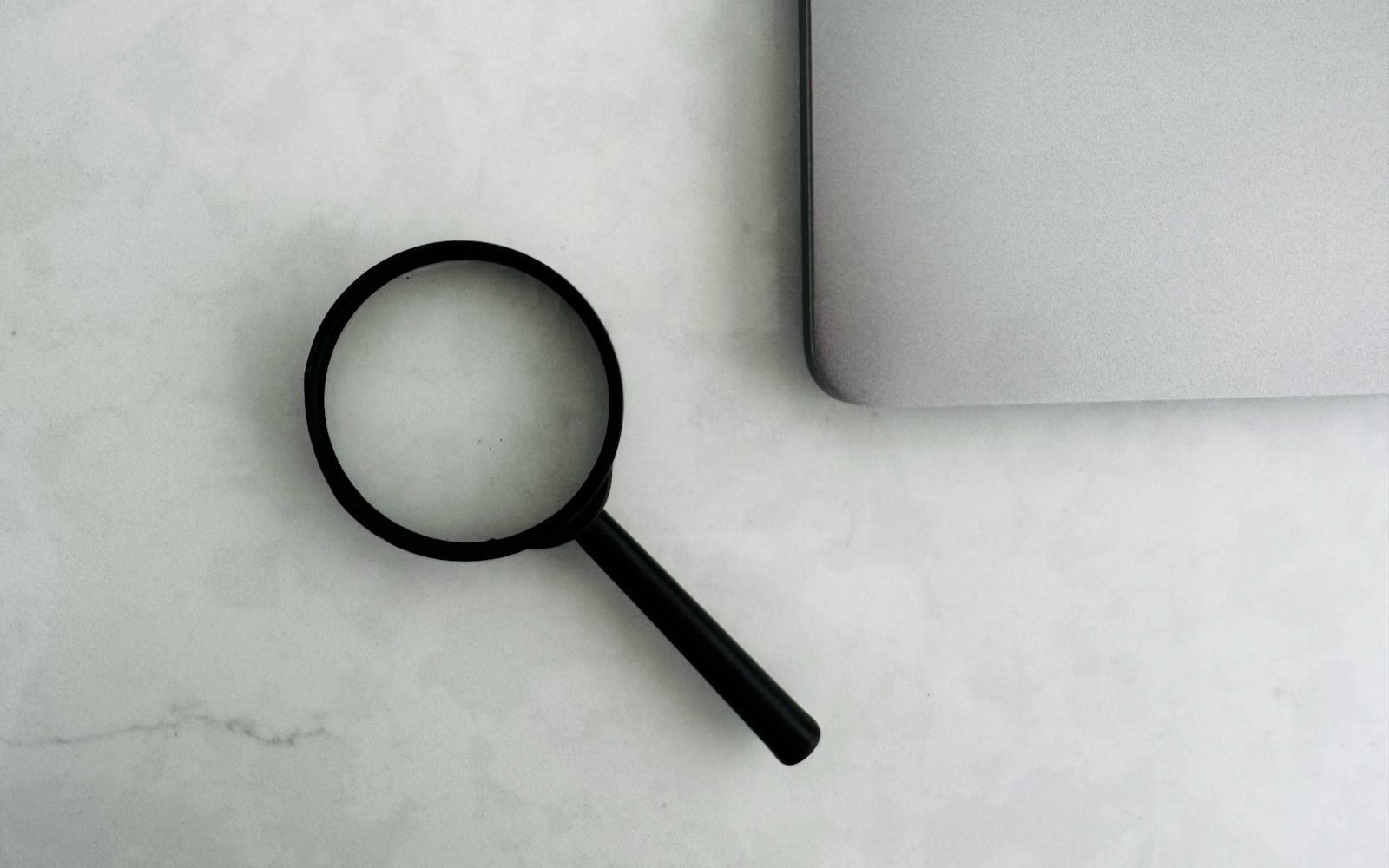 Lupa junto a una computadora portátil sobre un escritorio